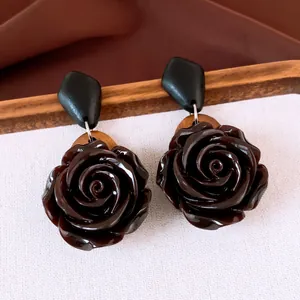Detail van vintage hars rozen oorbellen met houten accenten en een glanzende afwerking