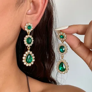 Détail de boucles d'oreilles pendantes gouttes émeraude vintage sur modèle réel
