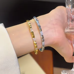 Detailweergave van luxe 18K vergulde en verzilverde armbanden met studs en zirkonia op de pols.