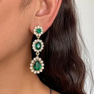 Gros plan de boucles d'oreilles pendantes vintage en strass vert émeraude sur l'oreille