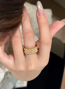 Close-up of elegant 18k gold plated open ring with pearls and zircons on finger