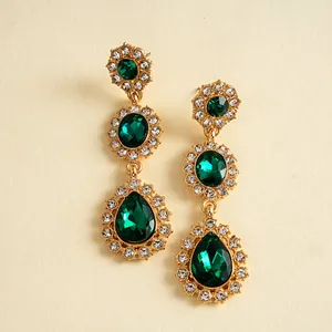 Gros plan de boucles d'oreilles vintage avec pierres en goutte vert émeraude et strass clairs