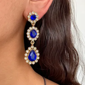 Gros plan de boucles d'oreilles style palais vintage avec cristaux bleus et monture dorée