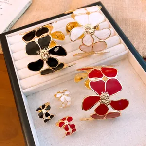 Nahaufnahme von stilvollem Emaille-Blumen-Armband und Ring-Set in Schwarz, Weiß und Rot.