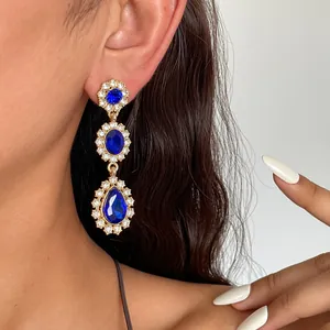 Vue détaillée de boucles d'oreilles pendantes dorées vintage avec cristaux bleu foncé