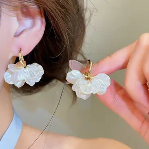 Vue détaillée de boucles d'oreilles dorées 14 carats avec pétales blancs nacrés.