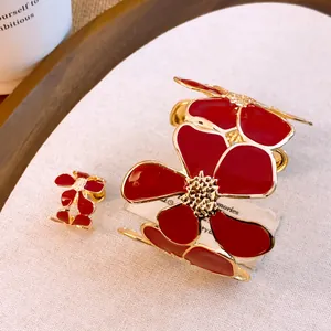Nahaufnahme eines luxuriösen Schmucksets mit roter Emaille-Blume, Armreif und offenem Ring