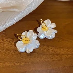 Gros plan d'élégantes boucles d'oreilles créoles en perles et pétales plaqués or 14 carats