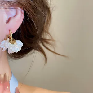 Vue détaillée d'élégantes boucles d'oreilles créoles à pétales blancs dorées 14 carats