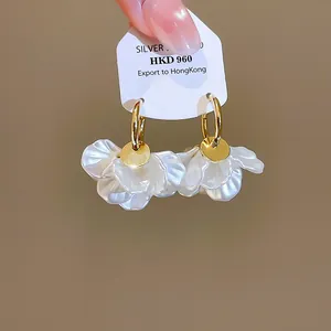 Gros plan de boucles d'oreilles créoles à pétales dorés 14 carats avec fleurs.