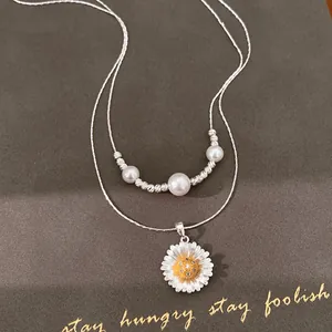 Detailansicht einer süßen Doppelhalskette mit Perlen und einem Zirkonia-Blumenanhänger.