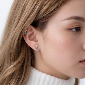Stylish angel wing titanium alloy stud earrings with blue gemstones on female ear