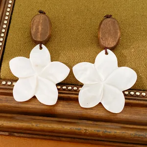 Detaillierte Makroansicht von weißen Blumenohrringen mit Naturholzperlen auf Vintage-Hintergrund