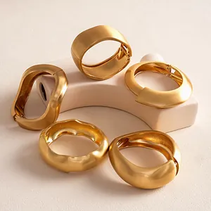 Collection of matte gold irregular geometric bracelets displayed on minimalist plaster block
