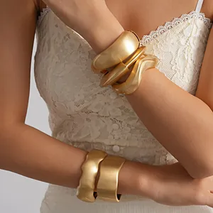Detailed view of matte gold irregular twisted geometric bracelets on a model's arm