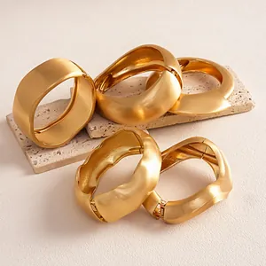 Detailed view of matte gold irregular twisted geometric bracelets on a stone base.