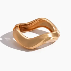Matte gold irregular twisted geometric bangle with a minimalist metal design aesthetic