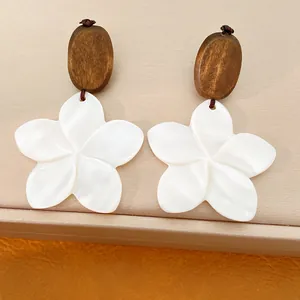 Makroansicht von Ohrringen aus Holz und weißer Muschelblüte mit Perlmuttglanz