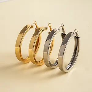 Nahaufnahme von polierten goldenen und silbernen geometrischen Creolen im minimalistischen Stil