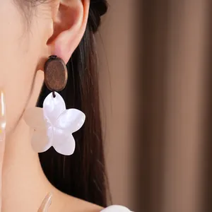 Detailansicht eleganter Ohrringe aus Holz und Muschelblüten an einem asiatischen Modell