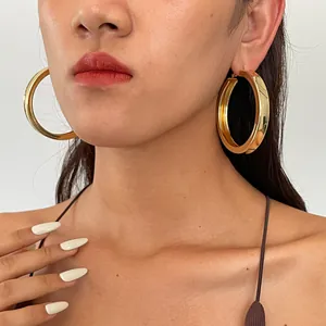 Nahaufnahme von großen goldenen dicken Creolen mit glänzendem Metallfinish am Modell