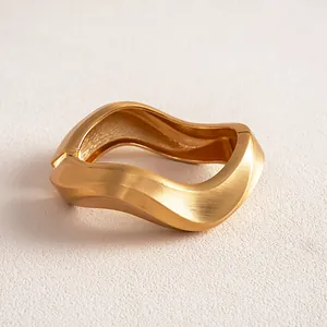 Detailed macro view of a matte gold twisted geometric bangle showing fine surface texture