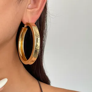 Nahaufnahme eines klobigen goldenen Creolen-Ohrrings, getragen von einem Modell