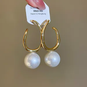 Nahaufnahme französischer Retro-Creolen aus Gold mit glänzenden großen Perlen