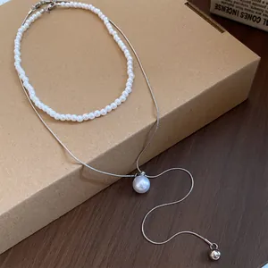 Vue détaillée d'un élégant ensemble de deux colliers avec perles et chaîne en argent.
