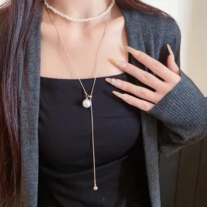 Gros plan sur l'ensemble collier ras du cou en perles et pendentif doré français