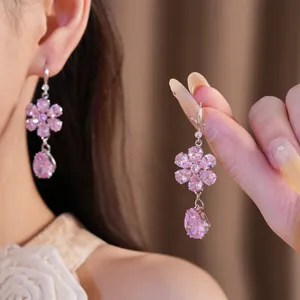 Close-up of pink zircon flower and teardrop earrings with elegant light effects.