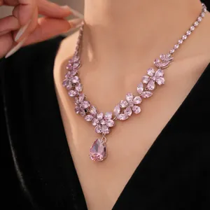 Close-up of elegant pink zircon flower necklace with pear-shaped pendant on black dress