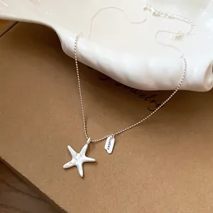 Close-up detail of silver starfish pendant necklace featuring LUCKY tag and crinkled texture