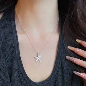 Close-up of a silver starfish pendant necklace with a lucky tag on a model
