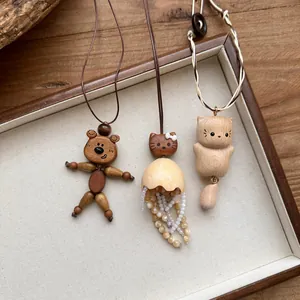 Detailed view of three handcrafted wooden pendants with cute animal designs on leather cords.