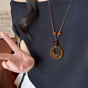 Retro amber acrylic round pendant necklace with brown cord, detail shot.