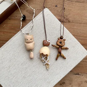 Handcrafted wooden animal pendant necklaces featuring cat and bear designs on a book
