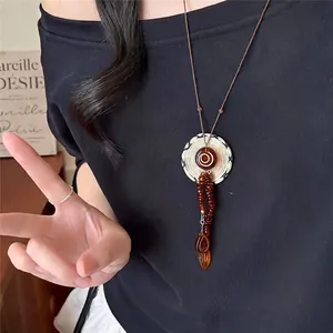 Close-up of a vintage acrylic round pendant necklace with brown cord worn by a model