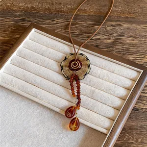 Macro view of vintage acrylic circular pendant with amber bead tassels on wax rope