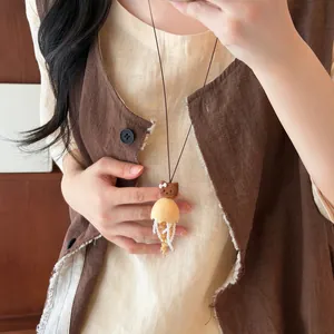 Detailed view of a wooden bear and shell jellyfish pendant necklace on an Asian model