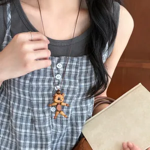 Detail view of a handcrafted wooden bear pendant necklace on a brown leather cord
