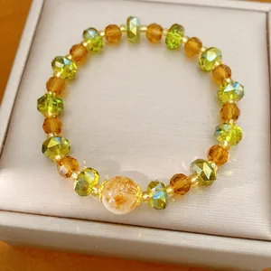 Gros plan détaillé de perles de verre à facettes vertes et ambrées sur un bracelet.