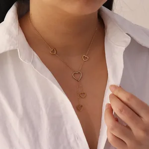 Elegant gold heart tassel necklace with sparkling pavé details on a white shirt background