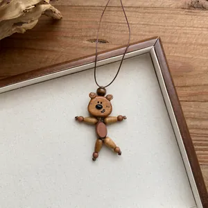 Close-up of cute wooden bear pendant necklace with leather cord on natural wood background