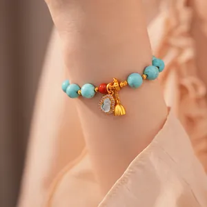 Detailansicht eines Türkis-Perlenarmbands mit goldenem Hulu-Anhänger für Damen