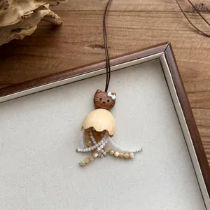 Detailed view of a handmade wooden cat pendant necklace with beaded tassels and leather cord