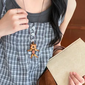 Detailed view of a handmade wooden bear pendant necklace worn with a leather cord