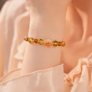 Gros plan d'un élégant bracelet en perles de verre ambrées et vertes au poignet
