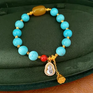 Nahaufnahme eines Retro-Perlenarmbands mit türkisfarbenen Perlen und einem Gold-Hulu-Anhänger