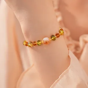 Gros plan d'un bracelet en perles de verre facettées porté au poignet aux tons chauds